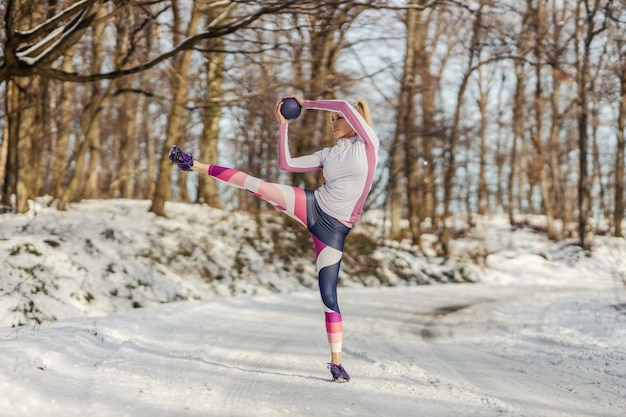 Apta a desportista fazendo exercícios com bola de fitness na natureza em dia de inverno nevado. Vida saudável, equipamentos de fitness, fitness de inverno
