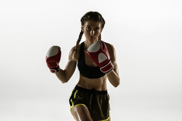 Apta a mulher caucasiana no boxe sportswear isolado na parede branca. novato boxeador caucasiano feminino treinando e praticando em movimento e ação. esporte, estilo de vida saudável, conceito de movimento.