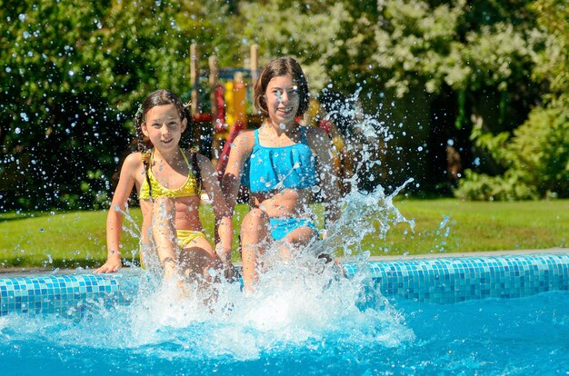 Aptidão do verão, crianças na piscina se divertem e espirram na água, crianças em férias em família