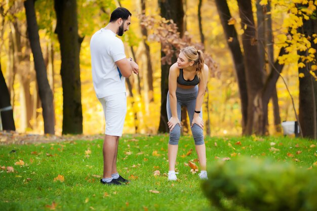 Aptitud. Entrenador personal toma notas mientras una mujer hace ejercicio al aire libre