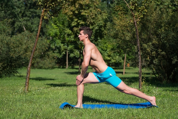 Aptitud física. Hombre musculoso entrenando en colchoneta de fitness al aire libre. fitness actividad de verano. hombre de fitness sobre la hierba verde. extensión.