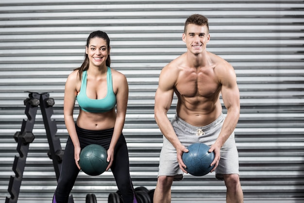 Foto apto casal fazendo exercício de bola no ginásio crossfit