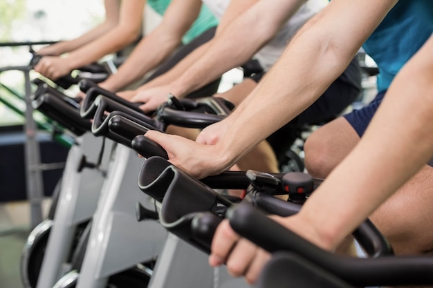 Apto grupo de pessoas usando bicicleta ergométrica juntos no ginásio