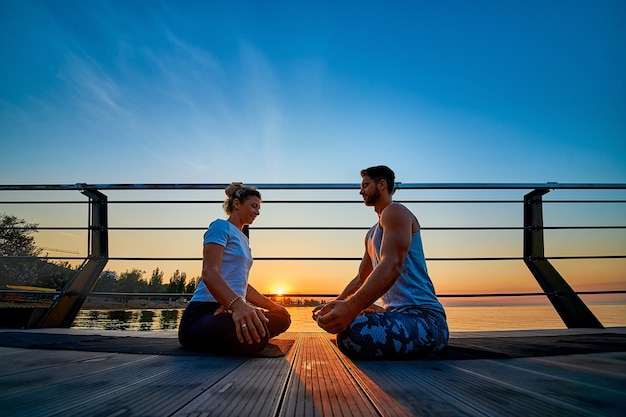 Apto jovem casal fazendo ioga pose de lótus estilo de vida saudável pessoas atividade de esporte ao ar livre em família vac ...