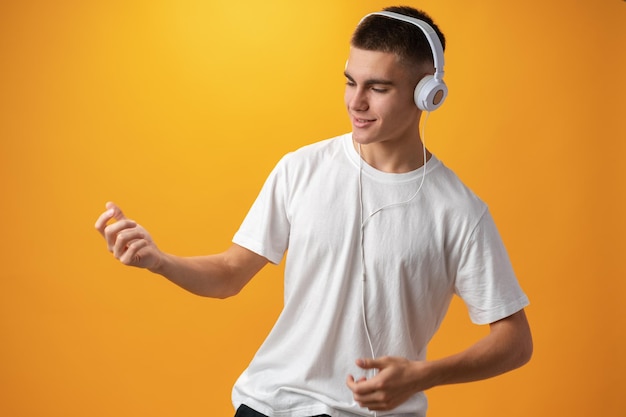 Apuesto adolescente con auriculares en la cabeza contra el fondo amarillo.