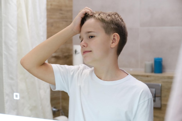 Un apuesto adolescente disfruta de su reflejo solo en el baño.