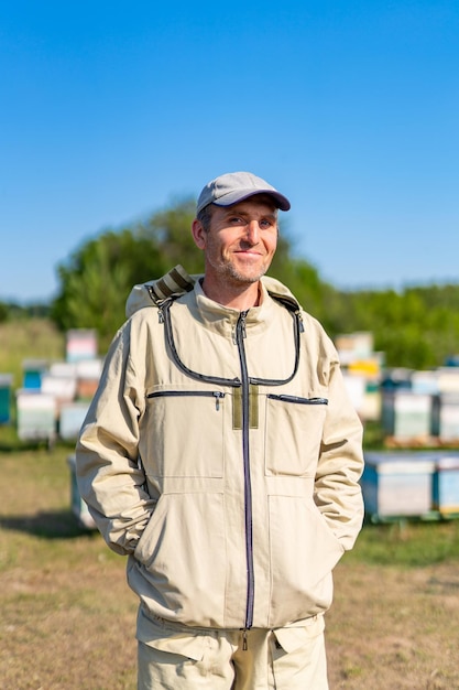 Apuesto apicultor en apiario Campo de panales con trabajador de abejas