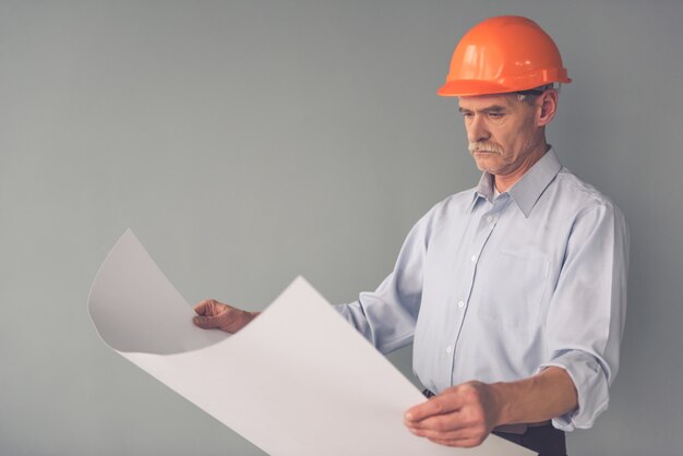 Apuesto arquitecto en casco protector está estudiando borradores