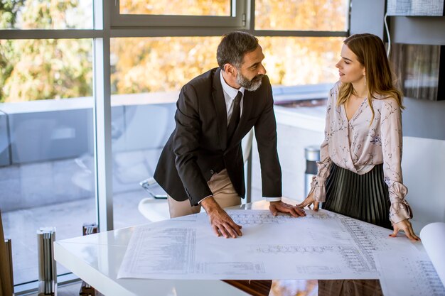 Apuesto arquitecto y su joven colega revisando planes y planos