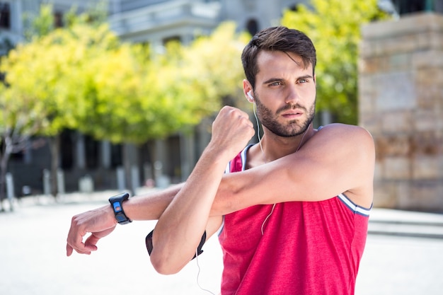 Apuesto atleta haciendo estiramientos de brazos