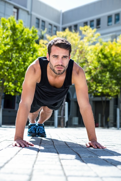 Apuesto atleta haciendo flexiones en el piso