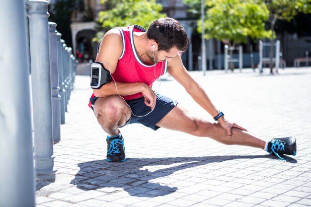 Apuesto atleta haciendo pierna estirando en el piso