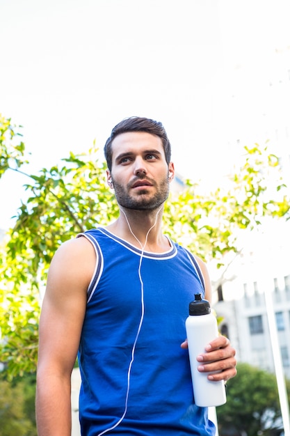 Apuesto atleta sosteniendo la botella