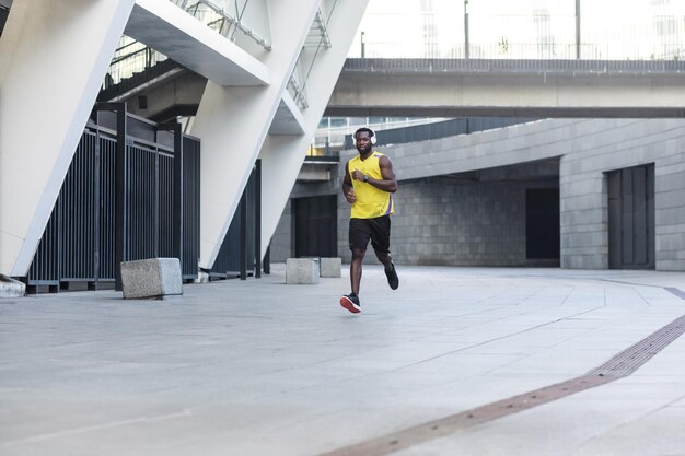 Apuesto corredor afroamericano entrenando y trotando en un día de verano