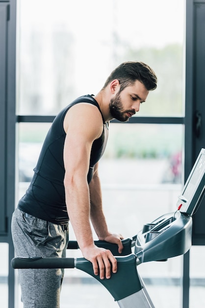 Apuesto deportista entrenando en cinta rodante en el centro deportivo