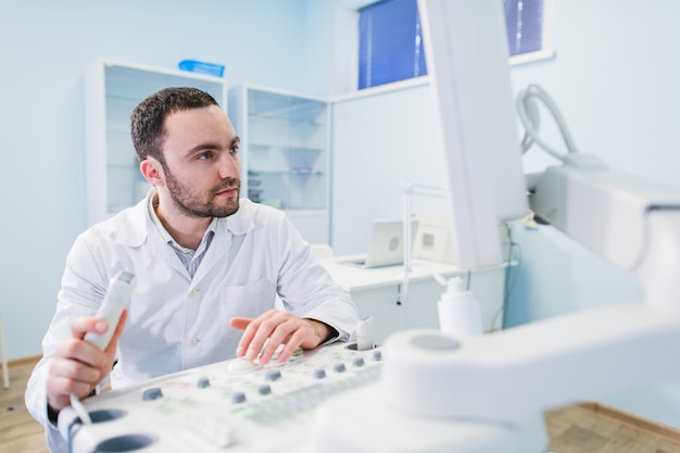 Apuesto doctor usando una máquina de ultrasonido