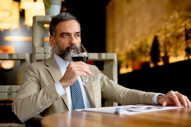 Apuesto empresario de mediana edad beber vino tinto en el restaurante