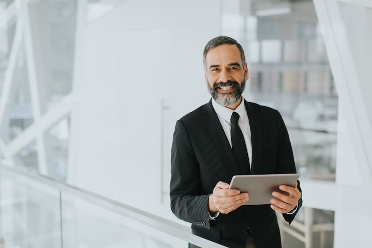 Foto apuesto empresario de mediana edad con tableta digital en la oficina moderna
