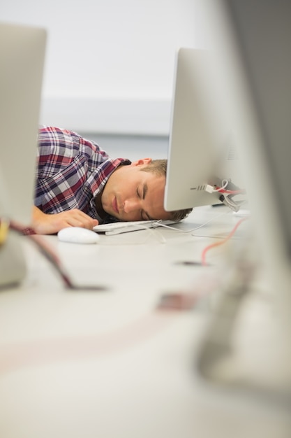 Foto apuesto estudiante durmiendo en la sala de informática