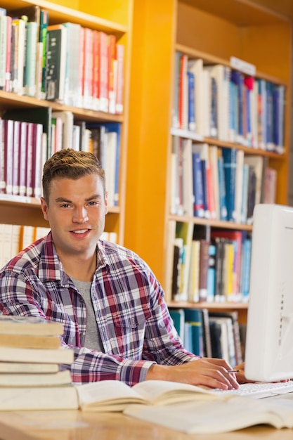 Apuesto estudiante sonriente usando la computadora