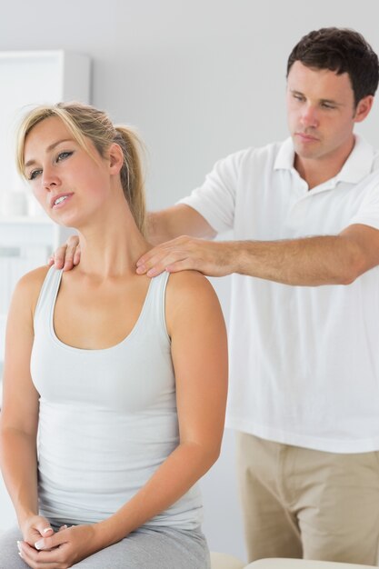 Apuesto fisioterapeuta masajeando el cuello de los pacientes