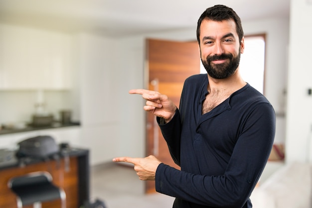 Apuesto hombre con barba apuntando a la casa interior lateral