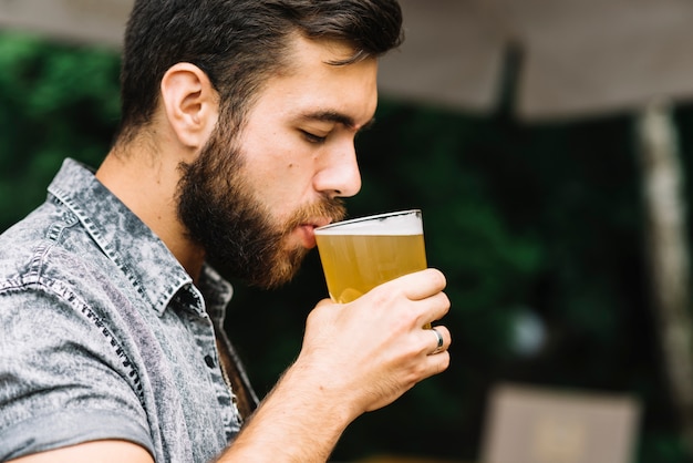 Apuesto hombre bebiendo un vaso de cerveza al aire libre