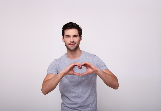 Un apuesto hombre blanco hizo un corazón con sus manos.