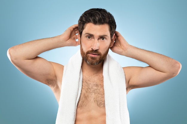 Apuesto hombre caucásico de mediana edad mirando a la cámara peinando el cabello o comprobando el problema de pérdida de cabello fondo azul