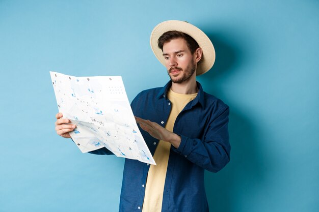 Apuesto hombre caucásico mirando el mapa de viaje, estudiando la ruta durante las vacaciones de verano