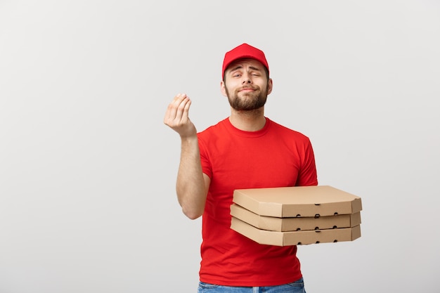 Apuesto hombre de entrega de pizza mostrando deliciosa expresión sobre fondo gris