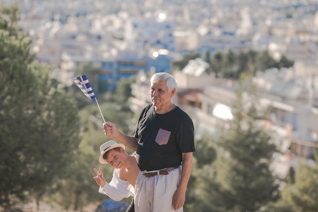 Apuesto hombre jubilado con cabello gris sosteniendo la bandera de Grecia símbolo nacional de Grecia