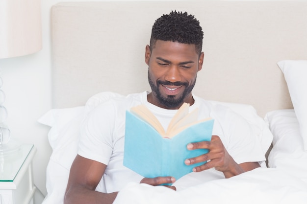 Apuesto hombre leyendo en la cama