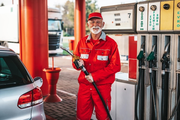 Un apuesto hombre mayor con barba trabajando en una gasolinera.