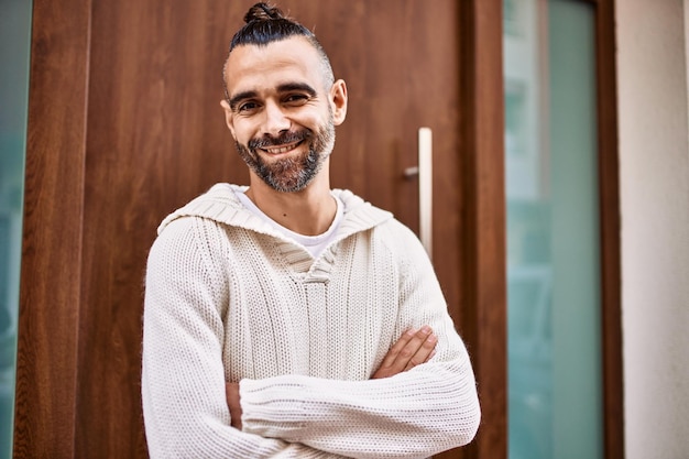 Apuesto hombre de mediana edad con barba de pie feliz y confiado en la ciudad