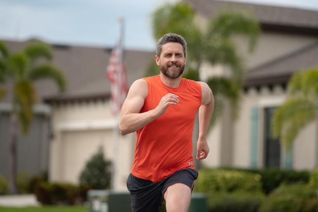 Apuesto hombre de mediana edad corriendo por el barrio americano atlético hombre corriendo saludable al aire libre l