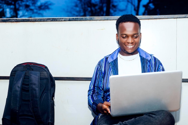 Apuesto hombre de negocios afroamericano alegremente usando laptop