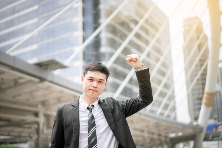 Un apuesto hombre de negocios asiático está muy contento por su éxito. Es un directivo que aporta beneficios crecientes a la empresa.