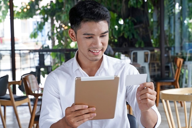 Apuesto hombre de negocios asiático u oficinista o joven estudiante mediante pago de crédito o débito
