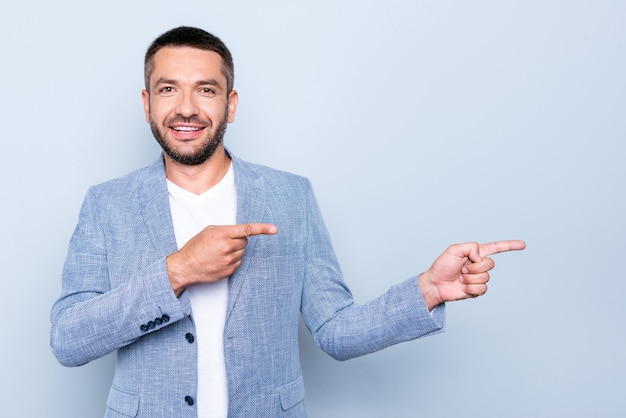 Apuesto hombre de negocios con una chaqueta azul posando contra la pared azul claro