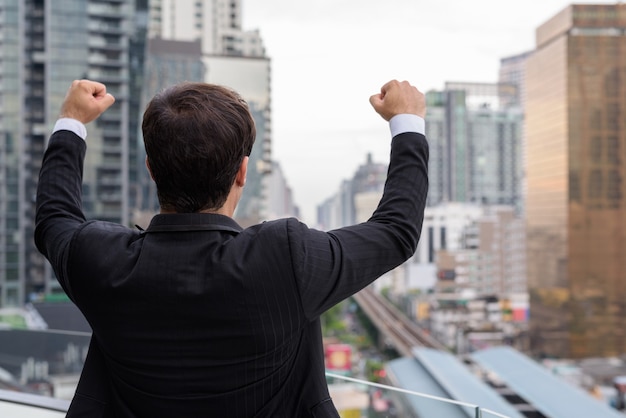 Apuesto hombre de negocios contra la vista de la ciudad