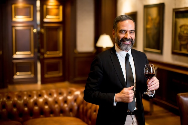 Foto apuesto hombre de negocios elegante bebiendo vino tinto en el bar