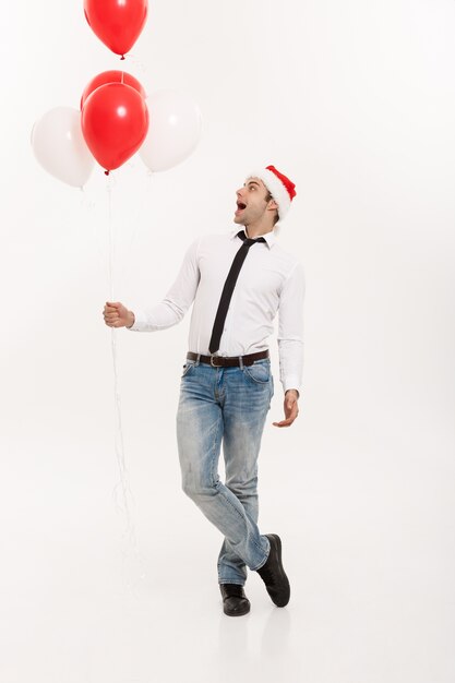 Apuesto hombre de negocios feliz caminando con globo rojo celebrar Navidad