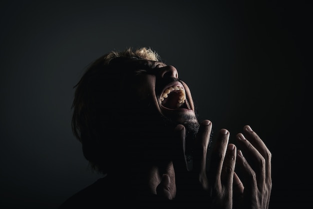 Apuesto hombre de negocios gritando como loco, Stressed con el trabajo. Retrato del estudio contra el fondo negro.