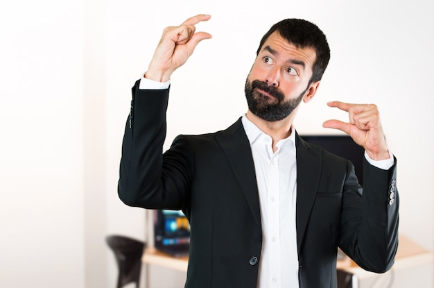 Foto apuesto hombre de negocios haciendo pequeña señal en la oficina