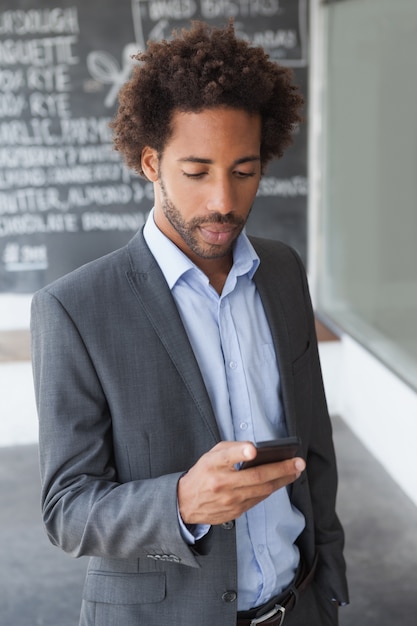 Apuesto hombre de negocios de mensajes de texto en el teléfono