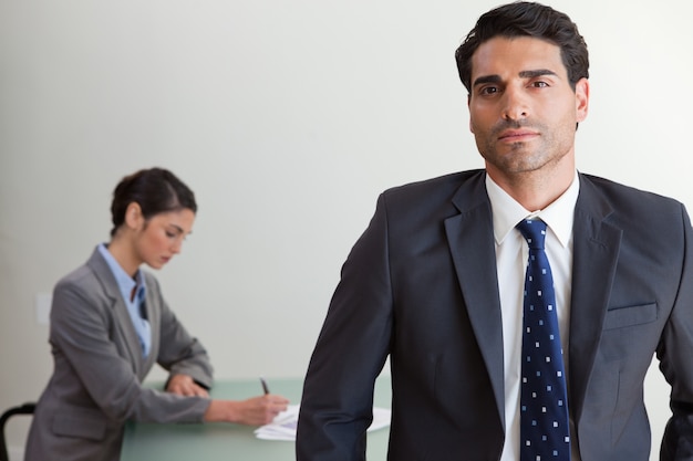 Apuesto hombre de negocios posando mientras su colega está trabajando