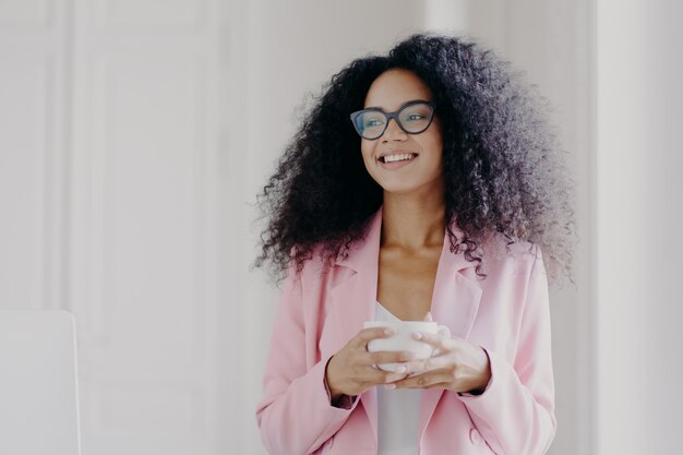 Apuesto hombre de negocios próspero afroamericano espera socio en la oficina, bebe café