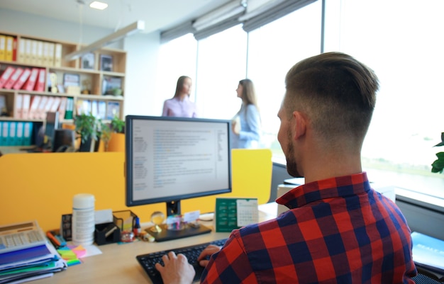 Foto apuesto hombre de negocios en ropa casual en el fondo de sus socios en la oficina creativa