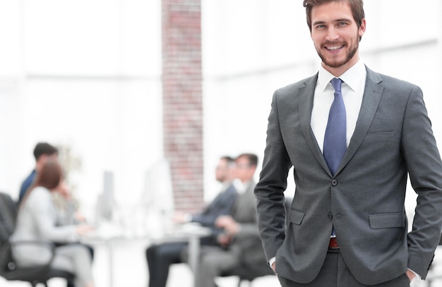 Apuesto hombre de negocios sonriendo con sus colegas detrás